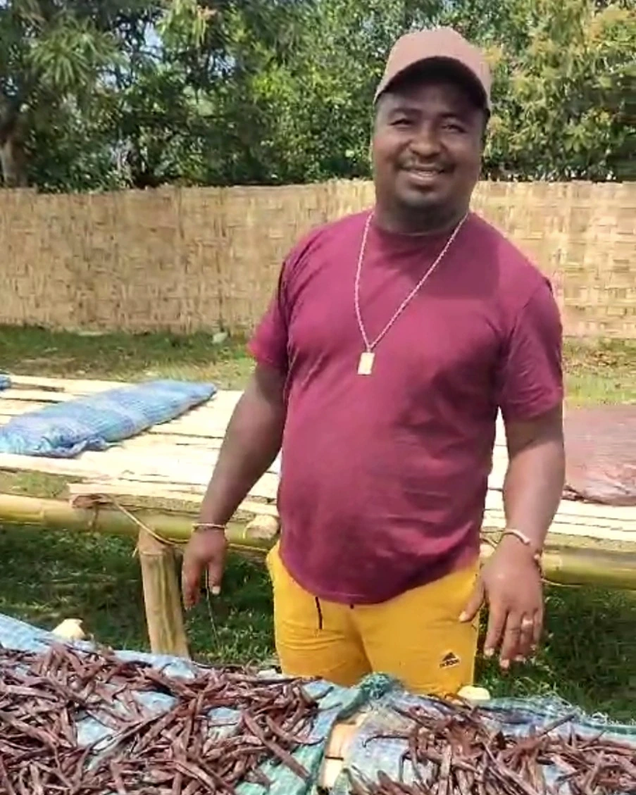 Landrique devant des gousses de vanille au soleil à Madagascar